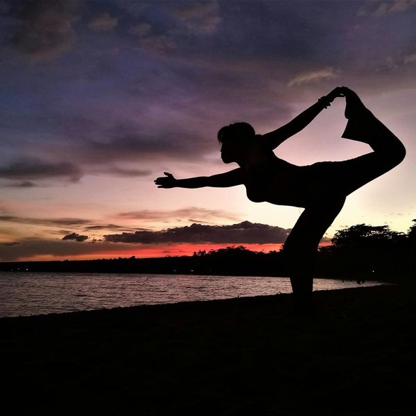 Silhouette of a person in a deep yoga stretch at sunset.